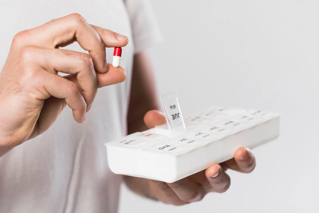 Close-up man holding pillbox with medicine